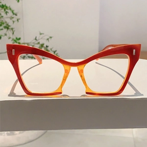 Detail of red and orange gradient cat-eye frame with metallic rivet accents and clear lenses
