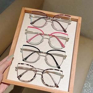Detailed close-up of cat-eye anti-blue light glasses frames in multiple colors in a tray