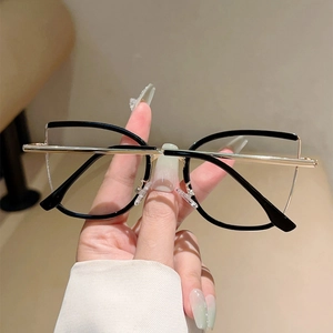 Detail of elegant black and gold cat-eye frame glasses held by hand with slim temples