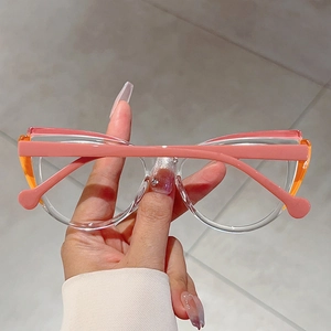 Detailed view of hand-held cat-eye glasses frame in pink and orange splice color