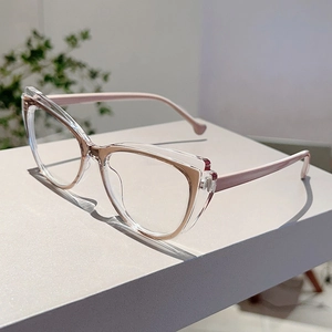 Cat-eye glasses detail showing transparent frame with rose gold inner rim on white block