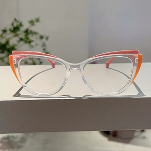 Detailed view of cat-eye glasses with transparent frame and pink-orange color blocking
