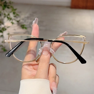 Dettaglio ravvicinato di occhiali cat-eye in metallo dorato con eleganti aste nere