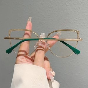 Detailed close-up of cat-eye glasses with gold hollow metal frames and green temples