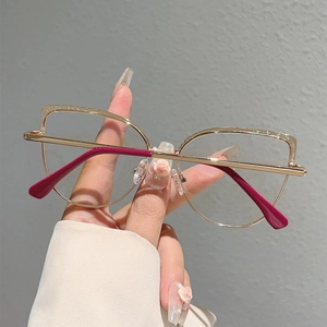 Detail of light gold metal cat eye glasses frame with rose red temple tips
