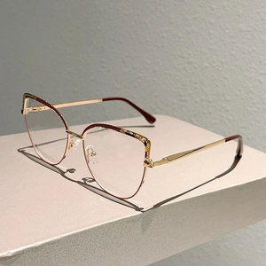 Detail of elegant cat-eye glasses frame with gold metal and burgundy accents on stand