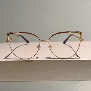 Detail of elegant gold cat-eye glasses with red enamel accents and spring hinges