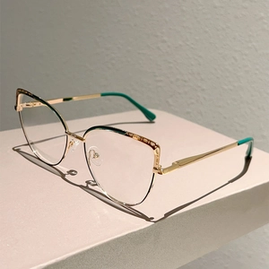 Macro detail of cat-eye gold metal frame with dark green accents on display stand