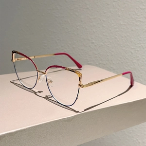 Detail of cat-eye glasses frame featuring dark red upper rim and golden metal temples