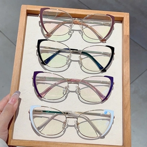 Detail of four cat-eye metal glasses frames in red black purple and white on wood