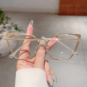 Détail de lunettes œil de chat dorées en métal avec charnières à ressort et verres clairs