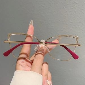 Detailed view of cat eye gold metal glasses with decorative floral bridge and red tips