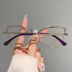 Detailed view of silver metal cat-eye frames with hollow geometric patterns on temples