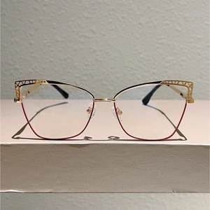 Close-up of gold cat-eye glasses frame featuring intricate hollow-out geometric patterns