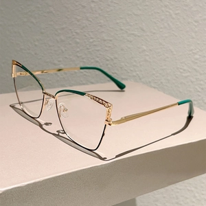 Close-up of golden cat-eye frames with hollow carvings and green lacquer accents