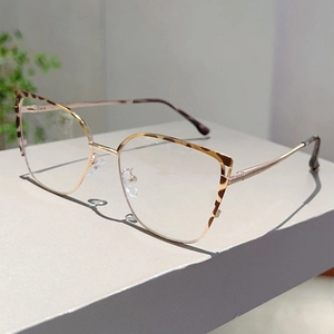 Detailed close-up of cat-eye glasses with leopard print and golden metal spring hinges