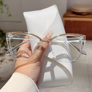 Close-up of clear cat-eye glasses with gold metal trim and white leather case