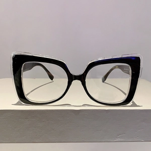Detail of cat-eye glasses frame featuring black and clear layers with tortoiseshell temples