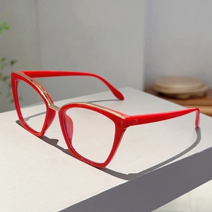 Detail of red cat-eye glasses with golden metal inlay on light grey geometric stand