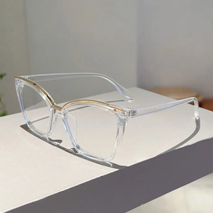 Detail of transparent square frame glasses with gold metal accent on a grey stand
