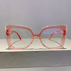 Front view of transparent pink cat-eye glasses frame on a minimalist grey display stand