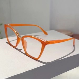 Detail of bright orange cat-eye frame with gold metal trim and transparent finish