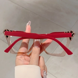 Detail of retro butterfly frame glasses with red temples and leopard print accent