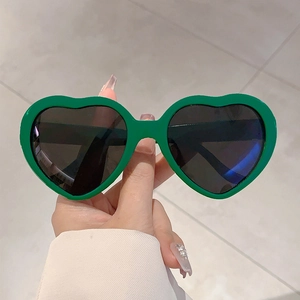 Détail de lunettes de soleil en forme de cœur avec monture vert vif et verres foncés