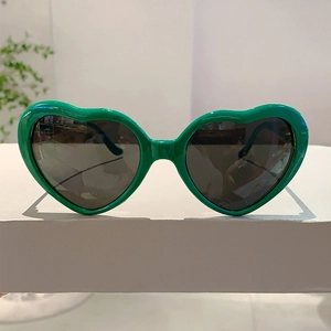 Gros plan de lunettes de soleil en forme de cœur vert vif avec verres foncés sur présentoir