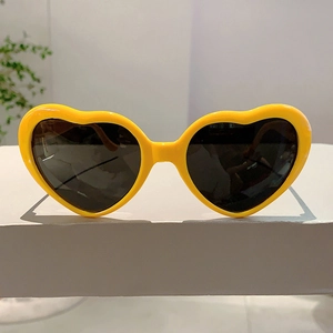 Gros plan de lunettes de soleil en cœur jaune vif avec verres foncés sur un socle
