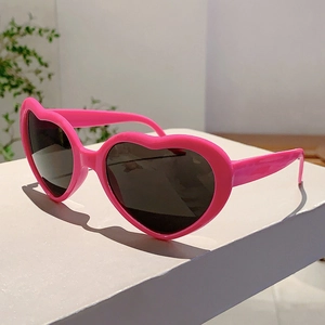Vue détaillée de lunettes de soleil roses en forme de cœur sur un présentoir blanc