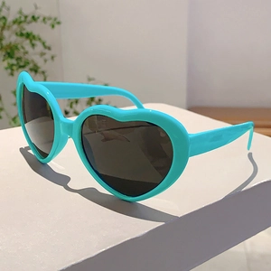 Détail de lunettes de soleil en forme de cœur bleu cyan avec branches larges et verres sombres