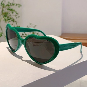 Gros plan sur des lunettes de soleil vert foncé en forme de cœur sur un socle