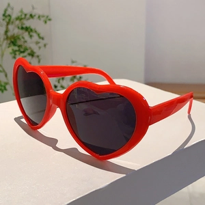 Gros plan de lunettes de soleil rouges en forme de cœur avec verres sombres sur boîte