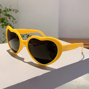 Détail de lunettes de soleil en forme de cœur jaune vif avec verres sombres et monture