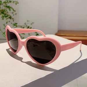 Vue détaillée de lunettes de soleil coeur rose avec verres foncés sur un présentoir