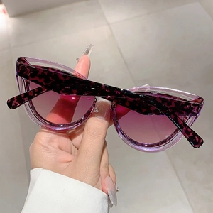 Detailed shot of purple cat-eye sunglasses with tortoise frame and gradient lenses