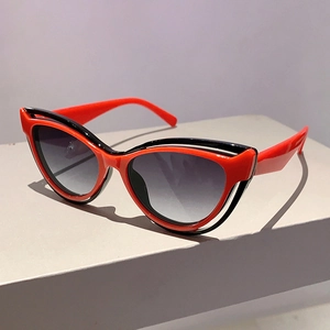 Detail of cat-eye sunglasses with dual-tone red and black frames and gradient lenses