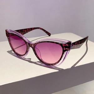 Detail of cat-eye sunglasses featuring red leopard tortoiseshell frame and gradient purple lenses