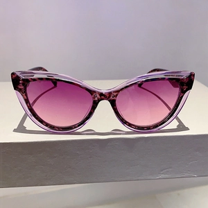 Detail of purple cat eye sunglasses with tortoise frame on a geometric stand