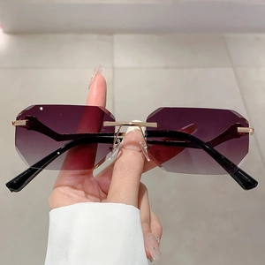 Close-up of rimless gradient sunglasses featuring geometric cut edges and gold metal bridge