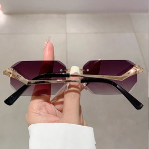 Detail of rimless polygon sunglasses with purple gradient lenses and gold panther accent
