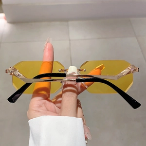 Close-up of yellow octagonal rimless sunglasses featuring a gold leopard head hinge detail