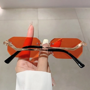 Close-up of golden panther emblem on rimless orange polygon sunglasses temples