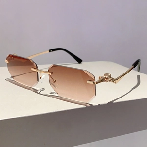Macro view of rimless gradient sunglasses with gold metal hinges and leopard head embossing