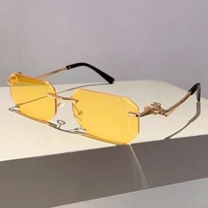 Detail of golden leopard head emblem on rimless yellow octagonal sunglasses frame