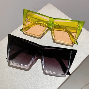 Détail de lunettes de soleil géométriques oversize aux montures vert néon et noir dégradé