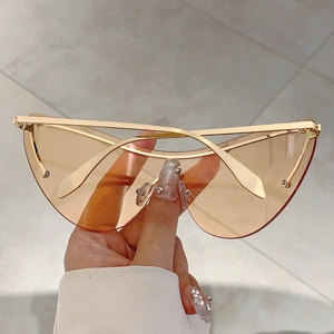 Détail de lunettes de soleil oversize sans monture avec verres orange et branches dorées