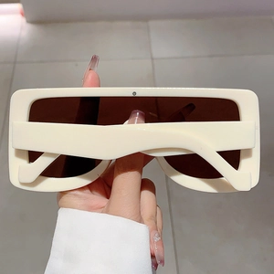 Close-up of oversized cream square sunglasses with thick frames and dark brown lenses