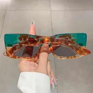Detail shot of rectangular tortoiseshell sunglasses with green color blocking and grey lenses